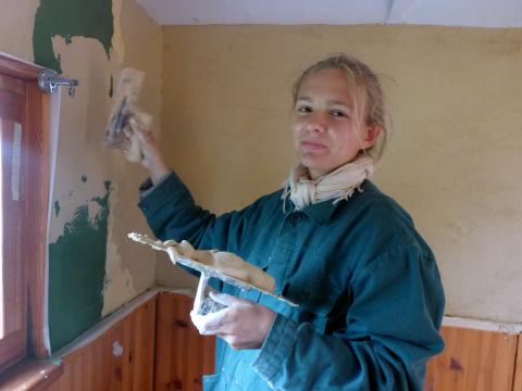 Emelie verputzt eine Wand in einem Bauwagen. | Foto: FAL e.V.